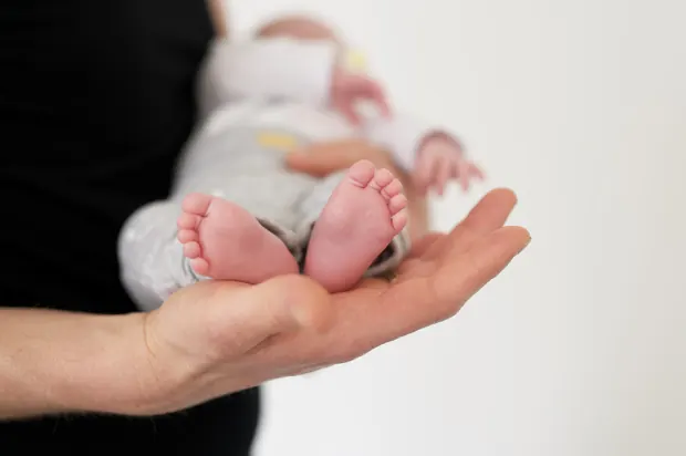 A newborn baby’s feet resting in an adult’s hands